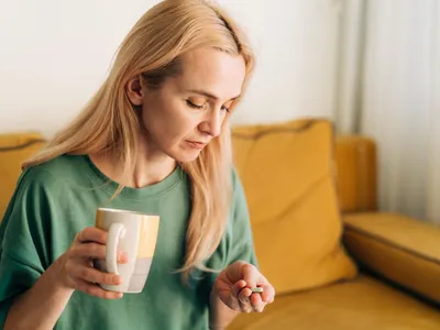 Femeie care bea cafea și administrează un medicament - Foto: Freepik (rol ilustrativ)