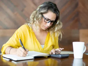 Femeie atentă făcând calcule privind banii pe care i-a acumulat la Pilonul II - Foto: Freepik/katemangostar