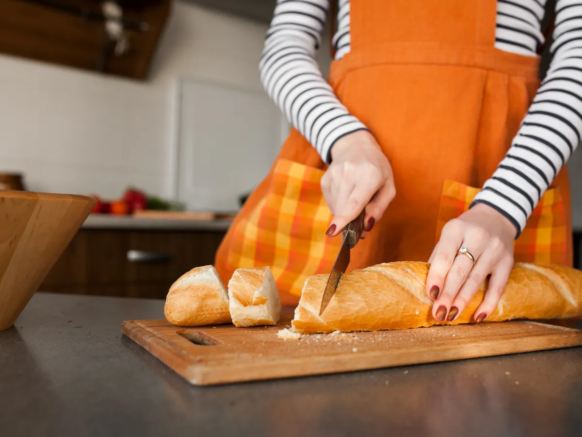Persoană care taie o pâine - Foto: Freepik (Imagine cu rol ilustrativ)