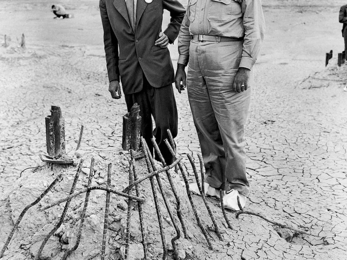 Generalul maior Leslie Groves, în dreapta, și Oppenheimer privesc baza turnului de oțel de care a atârnat bomba în timpul testului de lângă Alamogordo, New Mexico, în iulie 1945