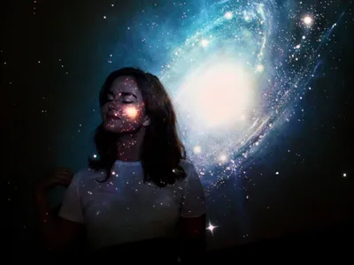 O tânără cu ochii închiși, stând în fața unei proiecții galactice - Foto: Pexels (Imagine cu rol ilustrativ)