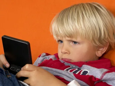 Copil privind concentrat un ecran de smartphone - Foto: Pexels (cu rol ilustrativ)
