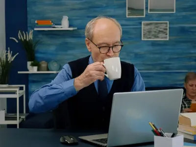 Bătrân bând cafea şi muncind by remote - Foto. Magnific.com/DC Studio