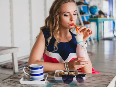Femeie frumoasă savurându-şi sucul şi cafeaua - Foto: Magnific.com/marymarkevich