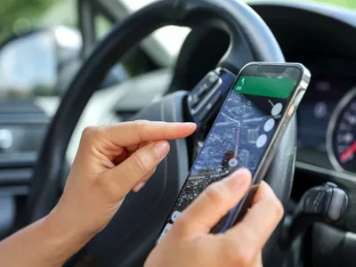 Şoferiţă ținând în mână un telefon cu interfață de navigaţie pe ecran - Foto: magnific.com/pvpproduction