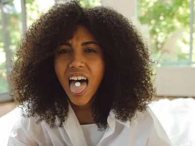 Femeie arătând cum ia o pastilă - Foto: Pexels/Polina Tankilevitch