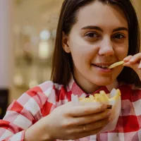 Femeie care mănâncă cartofi prăjiți - Foto: Feepik (imagine cu rol ilustrativ)