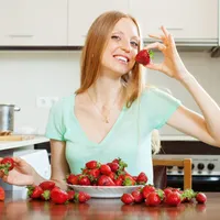 Femeie frumoasă care a așezat pe masă un bol cu căpșuni - Foto: Freepik