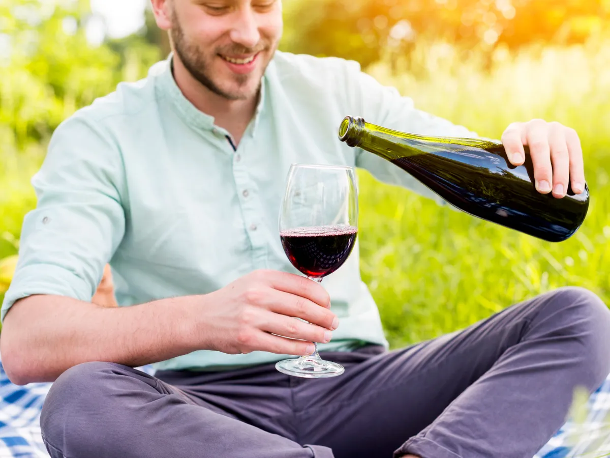 Bărbat turnând vin în pahar la picnic - Foto: Freepik (Imagine cu rol ilustrativ)