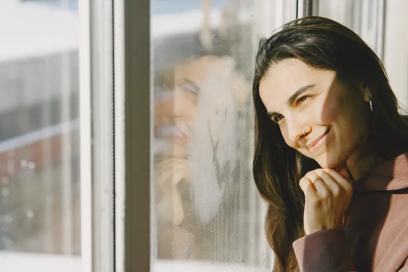 Femeie la fereastră - Foto: Magnific.com (Imagine cu rol ilustrativ)
