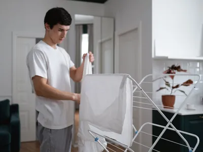 Un tânăr care manevrează rufe cu un uscător de rufe - Foto: Pexels (Imagine cu rol ilustrativ)