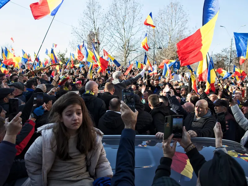 O fetiță a fost urcată pe o mașină de către tatăl ei în ultimul moment, altfel ar fi fost strivită de mulțimea dezlănțuită Foto: Mugur Vărzariu