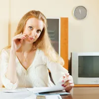 Femeie blondă uitându-se peste documente financiare - Foto: Freepik/bearfotos