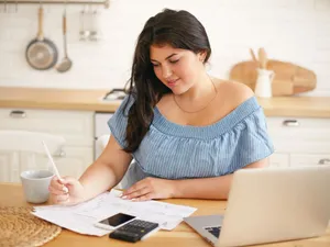 Tânără femeie calculând ce face cu economiile ei personale - Foto: Freepik/shurkin_son