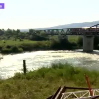 Podul stă pe mal, oamenii traversează cu bacul. FOTO: Digi 24