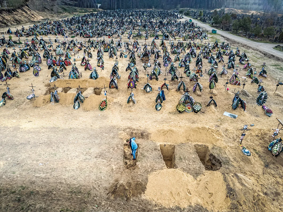 PĂMÂNT SFINȚIT Un gropar se pregătește pentru o înmormântare în masă, adăugând la rândurile de morminte din cimitir oameni uciși în timpul ocupației ruse a zonei