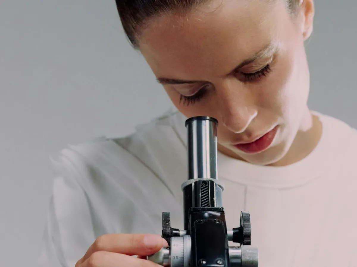 Cercetătoare analizând prin microscop o probă - Foto: Pexels/Ron Lach