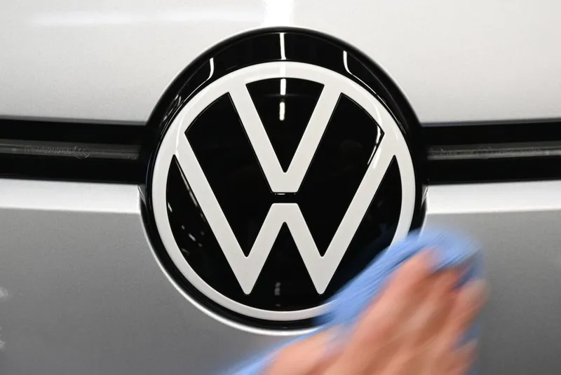 Un angajat lustruieşte logo-ul VW, de pe o maşină aflată pe linia de asamblare de la uzina din Zwickau, Saxonia - Foto: Profimedia Images