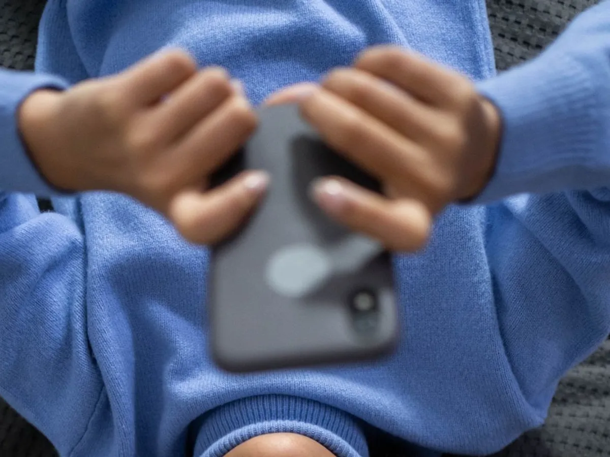 Femeie întinsă ţinând în mâini un smartphone - Foto: Pexels/cottonbro studio
