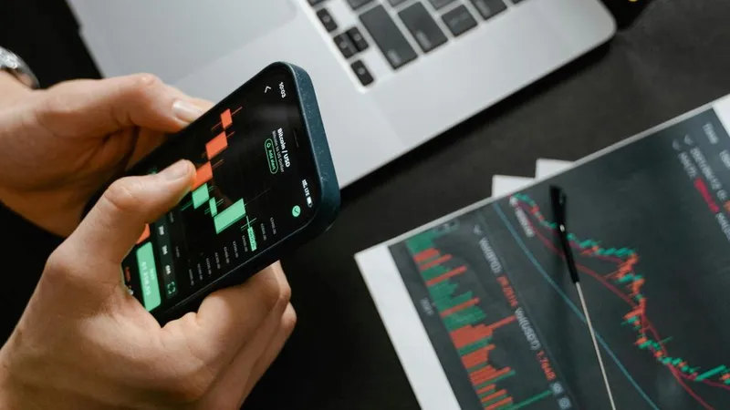 Persoană făcând calcule pe Bursă, pe telefonul său - Foto: Pexels/Tima Miroshnichenko