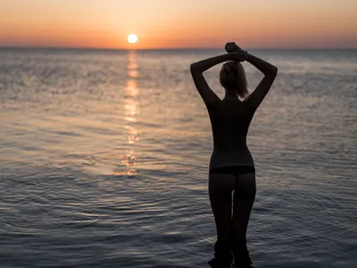 Femeie în costum de baie privind răsăritul la mare - Foto: Magnific (rol ilustrativ)