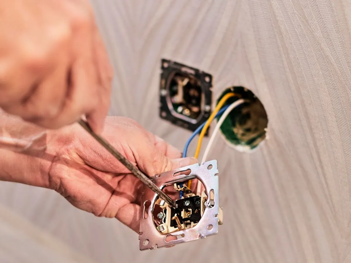 Un electrician montează o priză de curent electric - Foto: Magnific.com/ededchechine