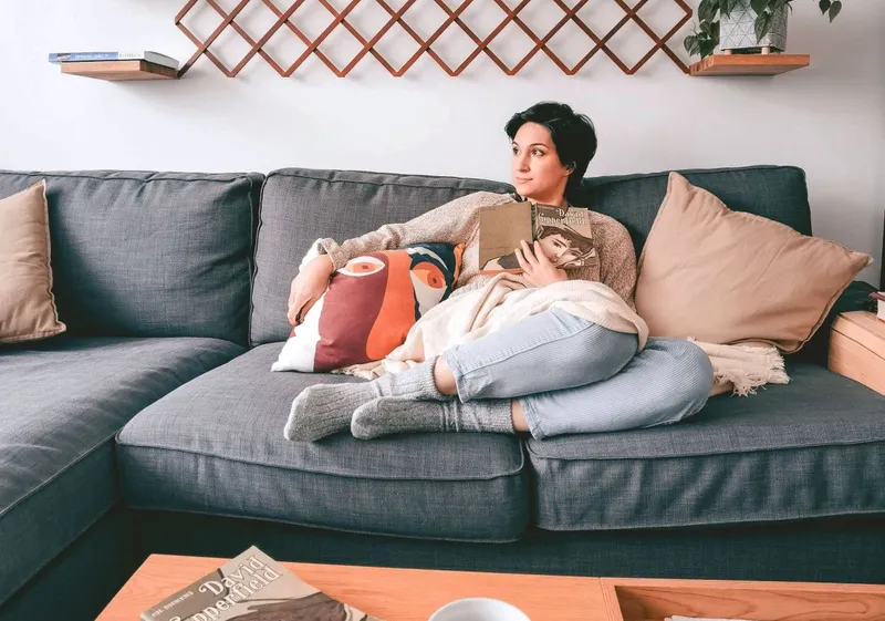 Femeie relaxată, st&acirc;nd pe sofa, &icirc;n caamera ei de zi - Foto: Pexels/Nicoleta S.