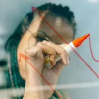 Femeie desenând un grafic, pe un panou transparent - Foto: Pexels/Nataliya Vaitkevich