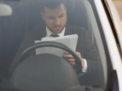 Șofer cu documentele în mână aflat la volanul mașinii - Foto