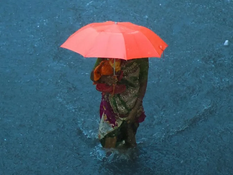 Femeie cu umbrelă mergând prin ploaia torenţială - Foto: Pexels/Aamir Dunkanwala