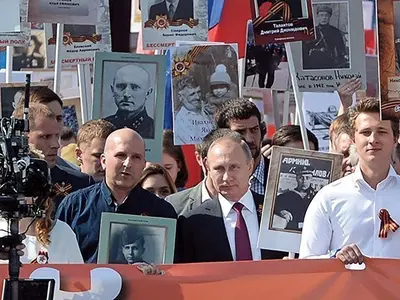 VLADIMIR PUTIN, cu fotografia tatălui său, care a luptat în Armata Roșie în timpul celui de-Al Doilea Război Mondial. Imaginea a fost răspândită de organul de propagandă al Rusiei, Sputnik.