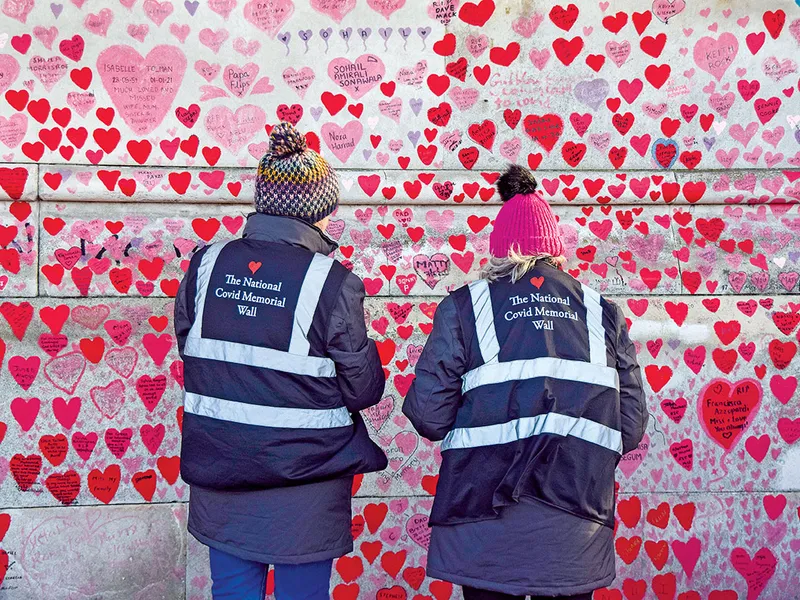 Voluntarii pictează inimi la Memorialul Național Covid din Londra.