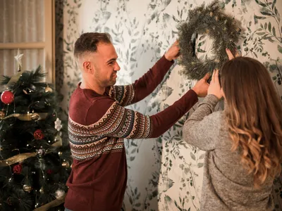 Cuplu care agață o ghirlandă pe pereți - Foto: Freepik (Imagine cu rol ilustrativ)