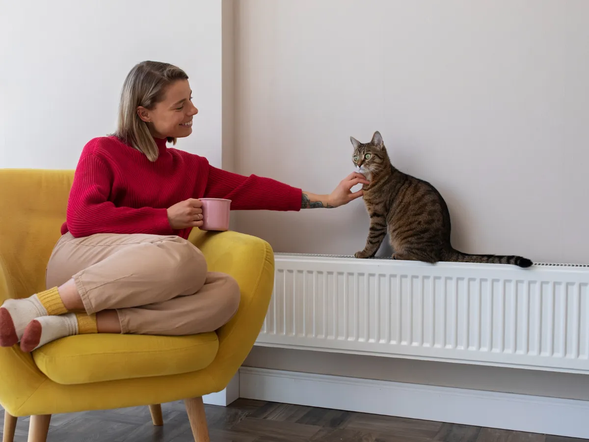 Femeie care stă lângă un calorifer - Foto: Freepik (rol ilustrativ)