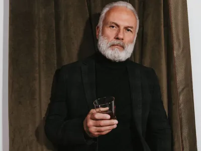 Bărbat în etate elegant, bând un pahar de whisky - Foto: Freepik/lookstudio