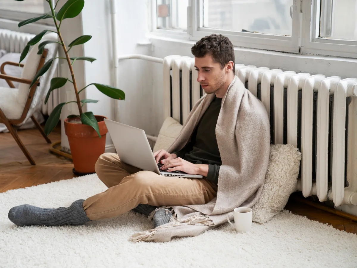 Persoană care stă lângă calorifer - Foto: Freepik (Imagine cu rol ilustrativ)