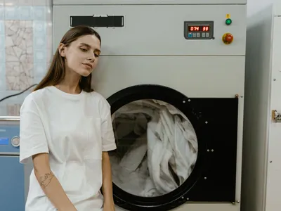 O femeie într-o spălătorie stă lângă o mașină de spălat - Foto: Pexels (Imagine cu rol ilustrativ)