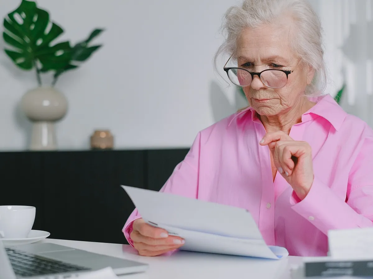 Pensionară se uită la acte