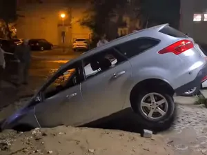 VIDEO O maşină s-a scufundat într-o groapă, în parcarea de domiciliu. Unde s-a întâmplat asta? - Foto: captură video Facebook