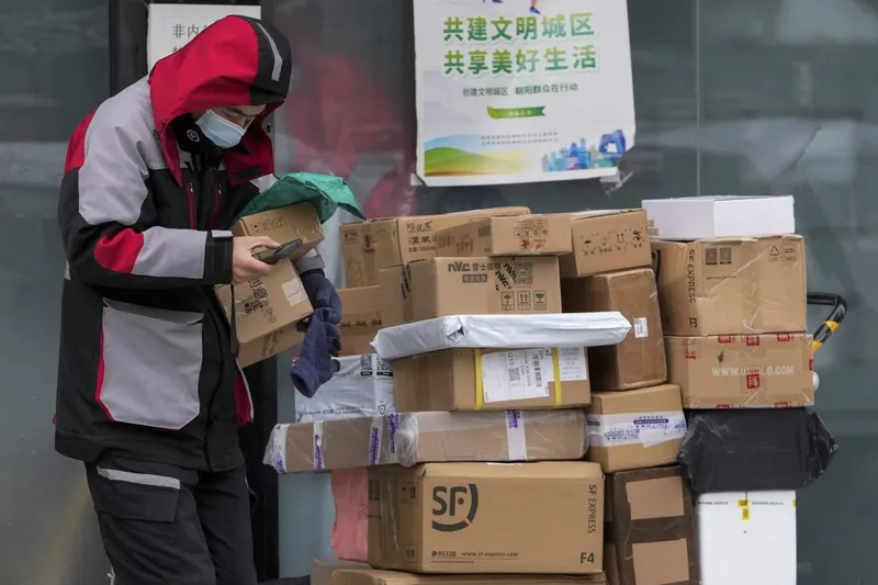 Se &icirc;nt&acirc;mpla &icirc;ncă din 2021. Un curier de la o companie privată ridică mai multe colete, pentru export, &icirc;n Beijing, China - Foto: Profimedia Images