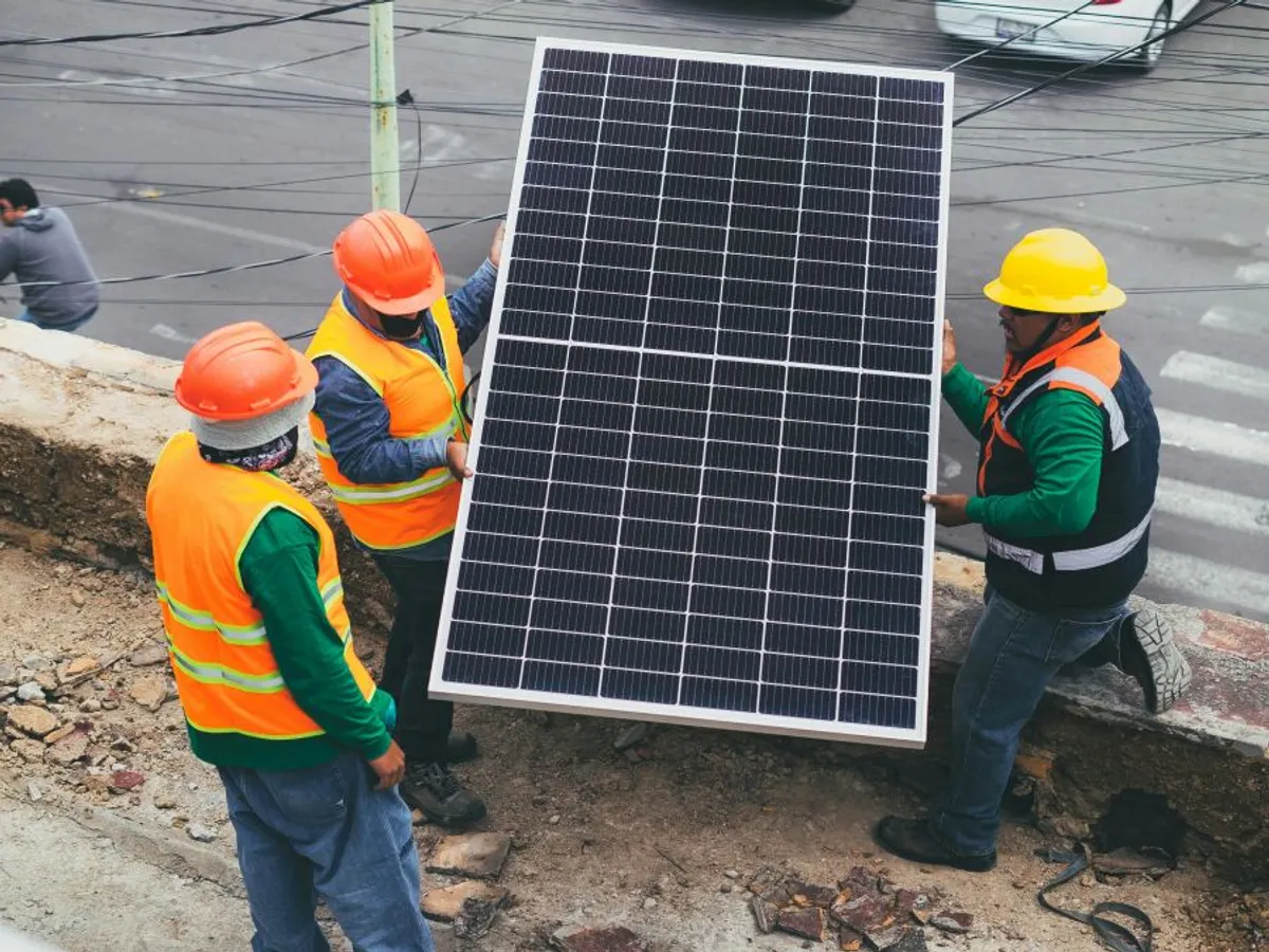Tehnicieni de fotovoltaice cărând un panou solar - Foto: Pexels/Los Muertos Crew