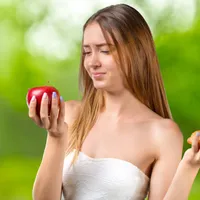 O femeie frumoasă care are în mână o piersică - Foto: Freepik