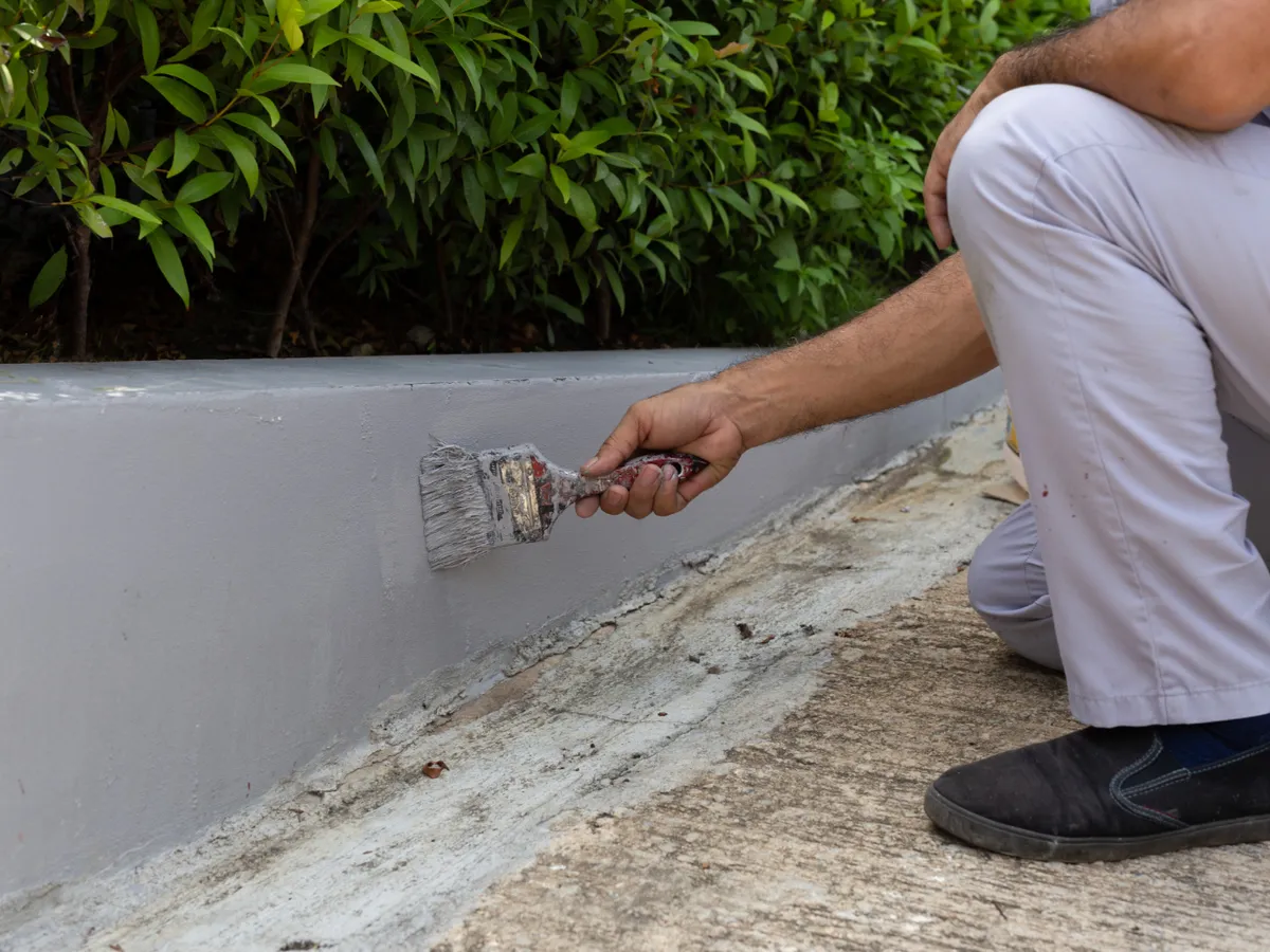 Muncitor care vopsește un perete de beton cu o pensulă - Foto: Freepik (Imagine cu rol ilustrativ)