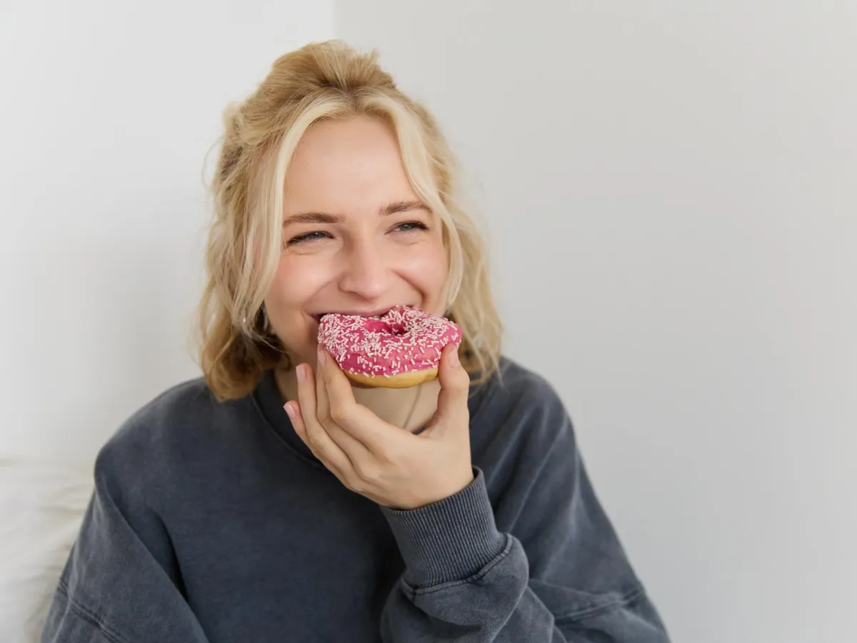 O tânără mănâncă o gogoașă