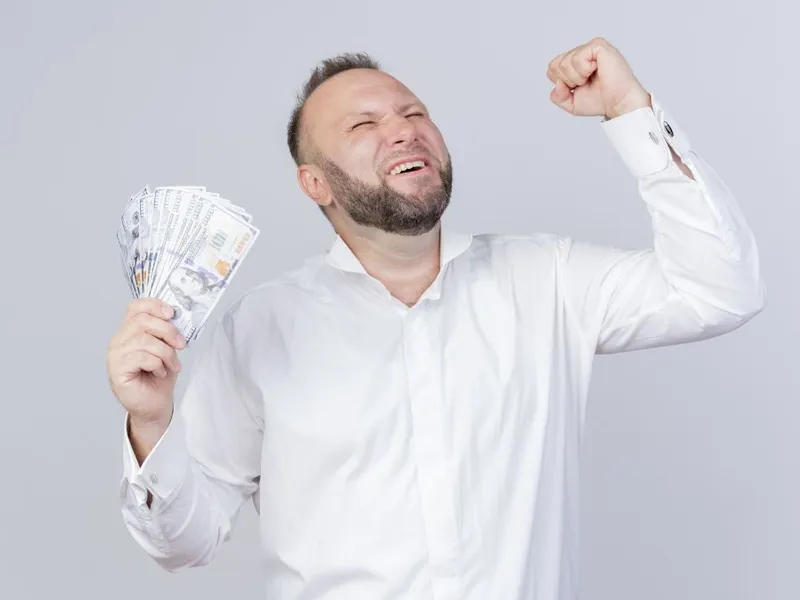 Bărbat fericit cu bancnote de dolari - Foto: Freepik/stockking