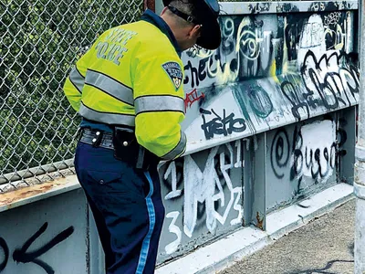 Polițistul Millet examinează grafitti-ul bandei, în aproprierea orașului Boston