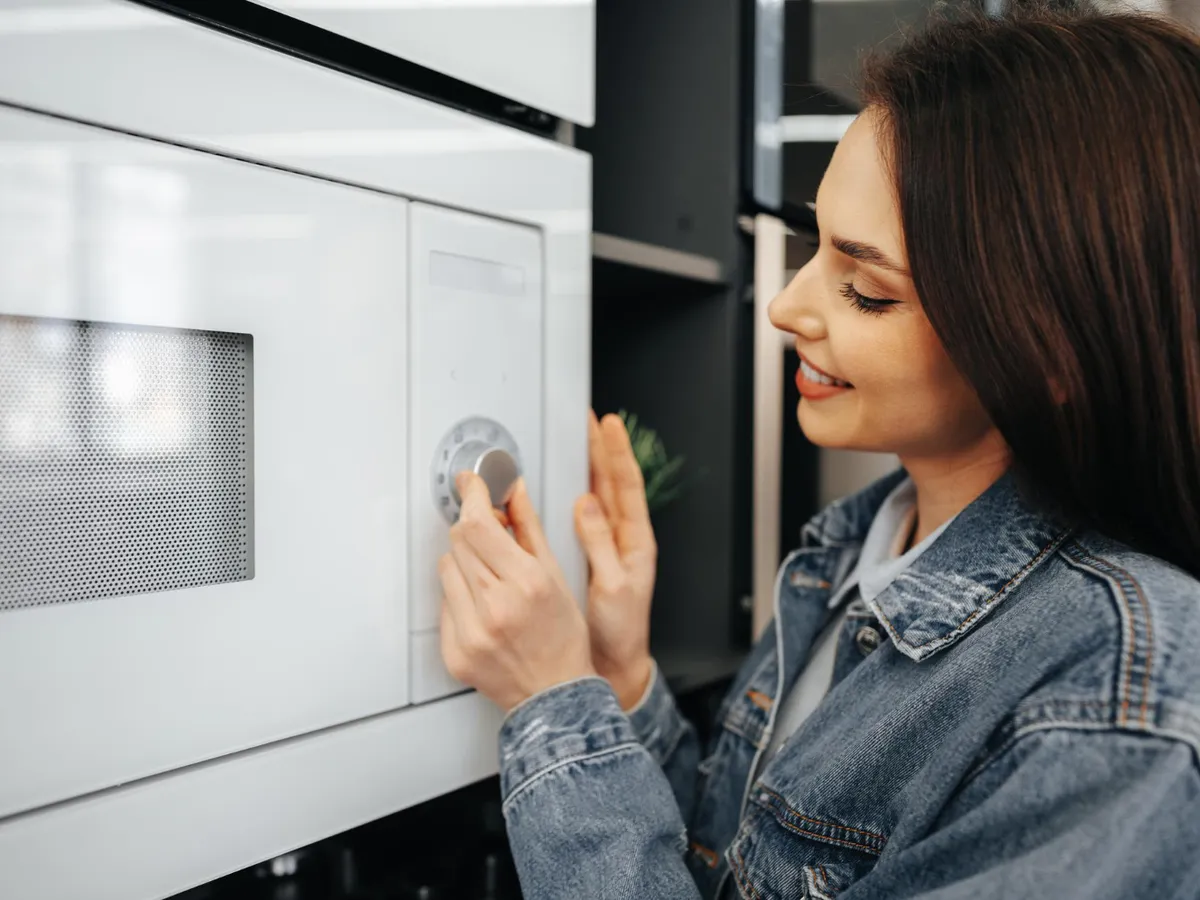 Persoană care deschide cuptorul cu microunde - Foto: Freepik (Imagine cu rol ilustrativ)