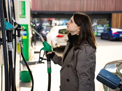 Femeie verificând preţul carburantului, în timp ce face plinul, la pompă - Foto: Profimedia Images