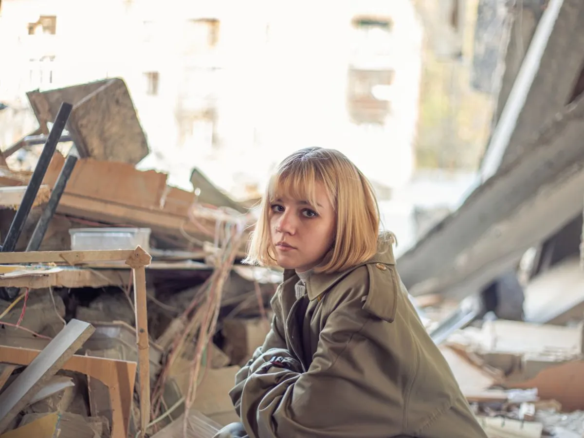 O femeie stă lângă o casă devastată de războiul din Ucraina - Foto: Magnific.com/pvproductions