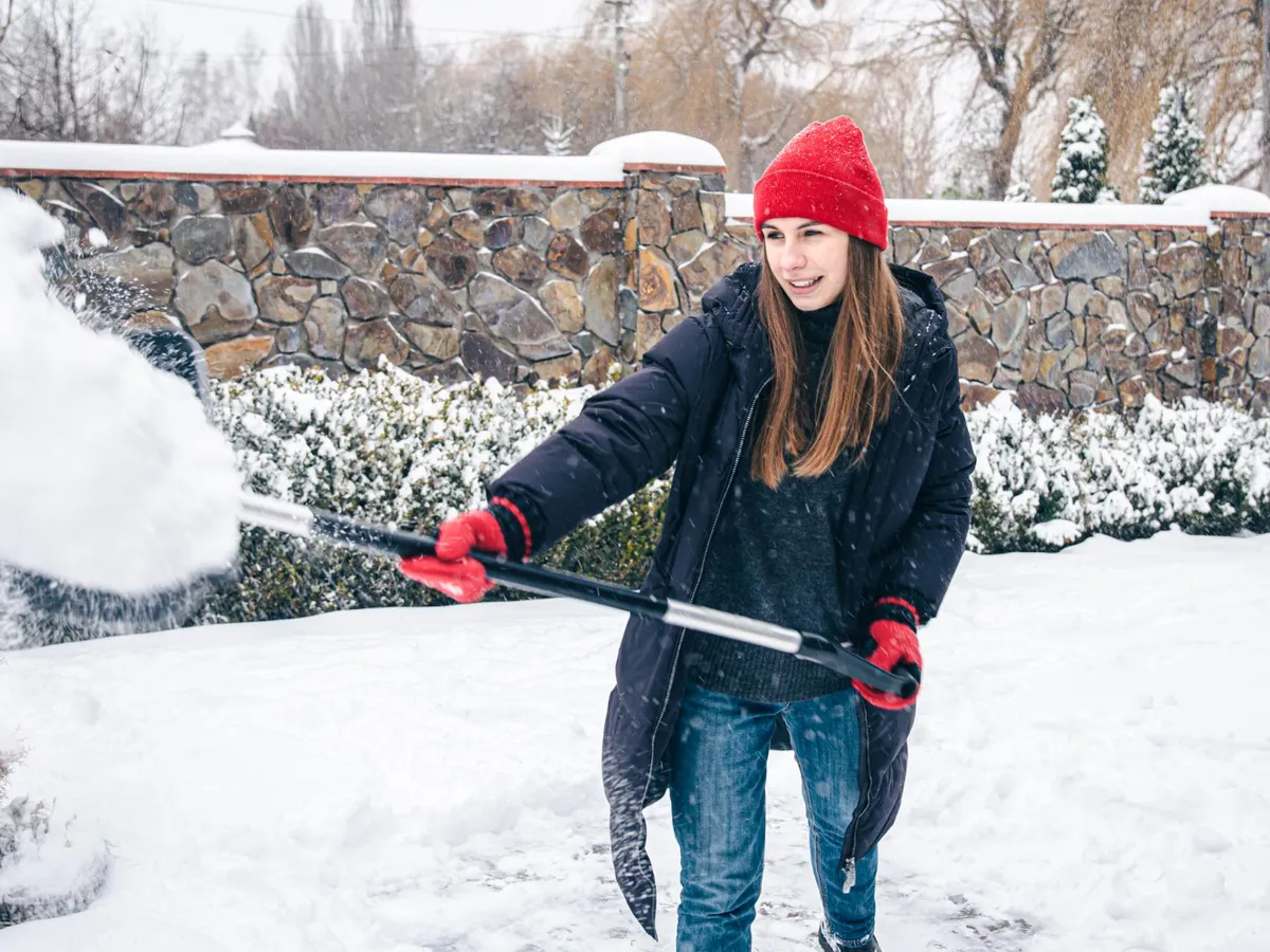 O tânără strânge zăpada din curte - Foto: freepik (rol ilustrativ)